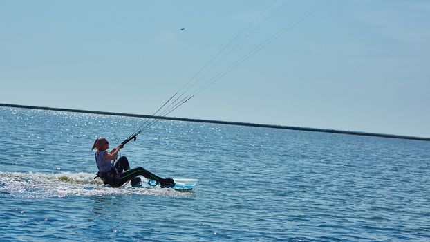 A young woman kite-surfer rides in summer day