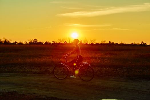 Biker girl at the sunset on the meadow