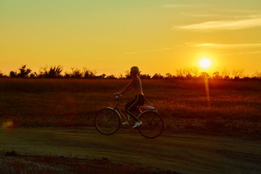 Biker girl at the sunset on the meadow