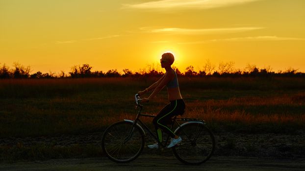 Biker girl at the sunset on the meadow