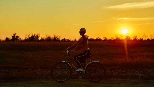 Biker girl at the sunset on the meadow