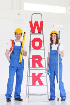 Two smiling professional workers with tools and WORK letters