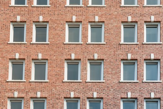 Red brick wall with rows of windows building exterior full frame.