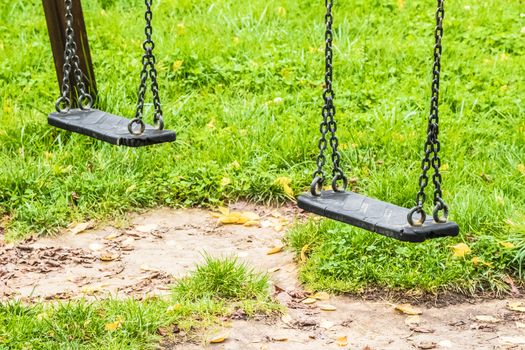 empty swings at playground for child, on green meadow background