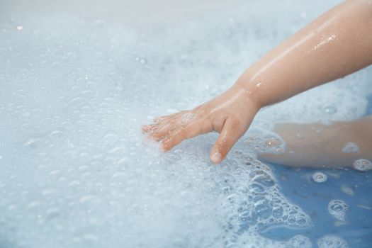 Hand of kid in the bath. Close-up horizontal photo