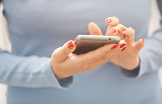 Woman with red manicure using smartphone. Horizontal photo