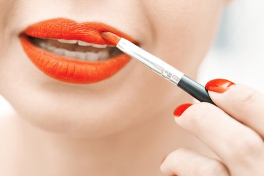 Woman applying red lipstick. Close-up view on face