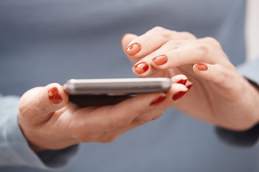 Woman with red manicure using smartphone. Horizontal photo