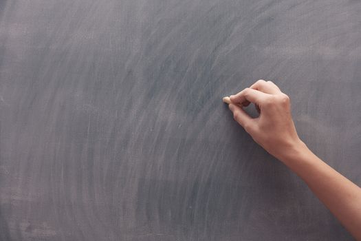 Human hand with chalk at the blackboard