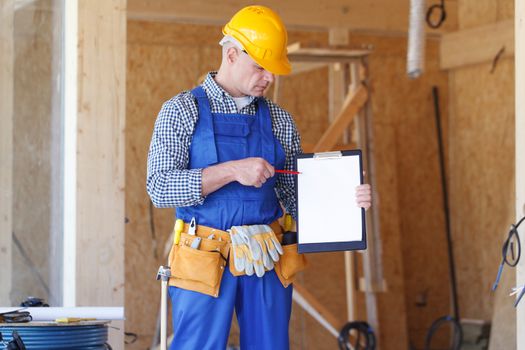 Construction foreman wearing a yellow safety helmet holding a clipboard