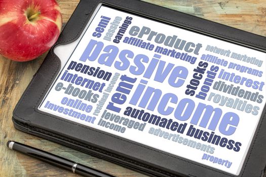 passive income word cloud  on a digital tablet with a red apple