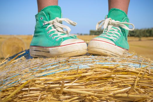 Feet of little girl on a hay bale