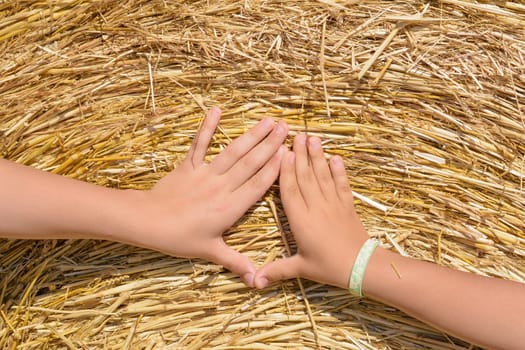 Hands of children on bale of hay
