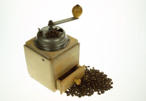 Old, historic, manual coffee grinder and a handful of coffee beans on isolated white.Horizontal view.