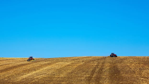 Agricultural Landscape. Tractors working on the field. Spring sunny day