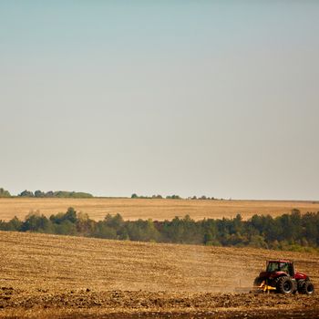 Agricultural Landscape. Tractor working on the field. Spring sunny day