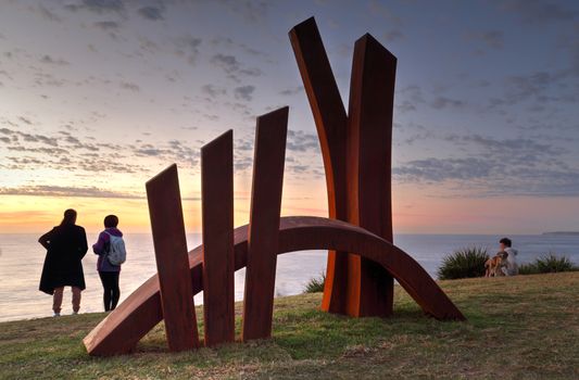 BONDI, AUSTRALIA - OCTOBER 25, 2015;  Annual Sculpture by the Sea  public event.  Exhibit titled The Bridge by Linda Bowden, made of Corten Steel being lit by the first light of the rising sun.