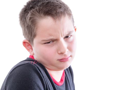 Head and Shoulders Close Up Portrait of Young Boy with Scrutinizing Facial Expression Glaring at Camera in Studio with White Background and Copy Space