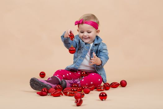 portrait of young cute baby on beige background with christmas balls