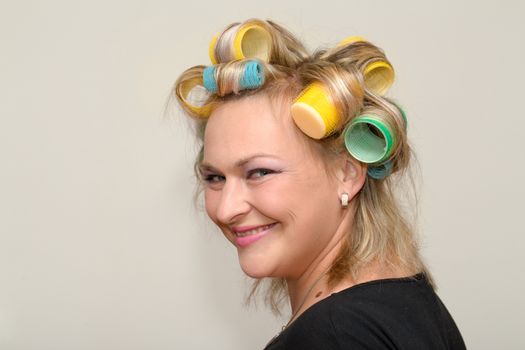 portrait of beautiful plus size young blond woman posing with home with curlers
