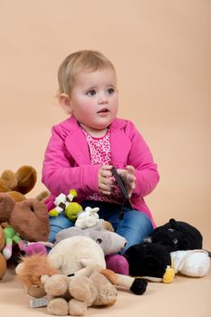 portrait of young cute baby on beige background with plushy toys