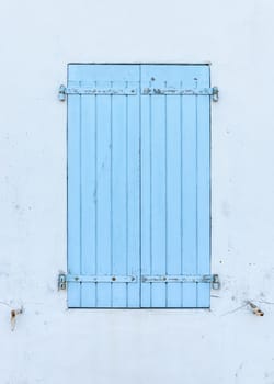 Closed blue wooden shutters, white wall