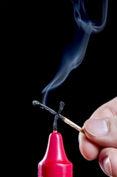 Red Candle Stick With Smoke and male hand with match.