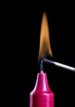 Red Candle Stick Burning with match and black background.