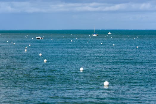 White buoys and boats, blue sea, in Noirmoutier Island, France