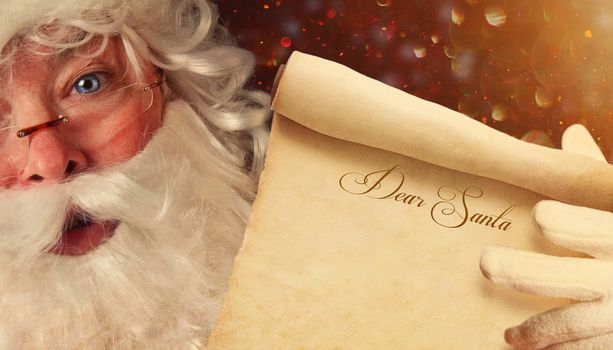 Closeup of Santa Claus holding a Dear Santa scroll 