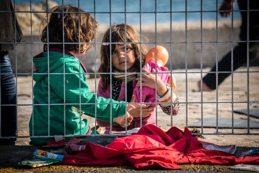GREECE, Mytilene: Two girls play as thousands of refugees wait to depart from Mytilene, the capital and port city of the Greek island of Lesbos, on November 7, 2015. From there, the refugees will make their way to the Port of Piraeus.