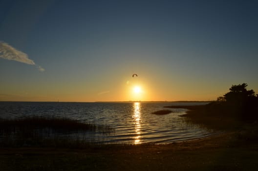 A wind surfer catching the last rays of sun over the water in North Carolina near Fort Fisher.