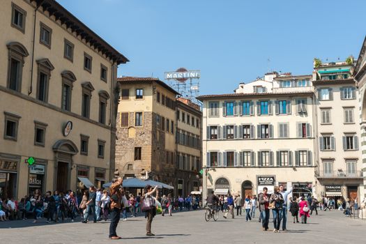 Florence, Italy the Paizza Del Duomo as it would have been, people crowd the street while typically Italian urban architecture and iconic retro Matini neon sign complete the picture.