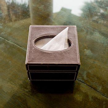 Tissue box made from leather on glass desk.