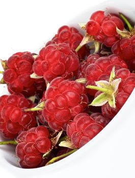 Big Ripe Raspberries with Fruit Stems in White Bowl isolated on white background