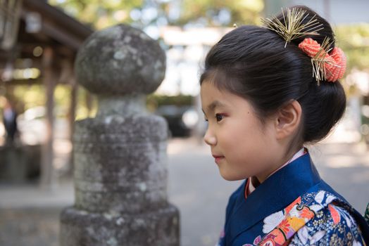 A young Japanese girl in a kimono outdoors at a shrine.