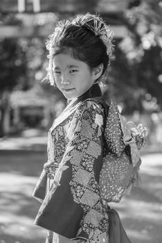 A young Japanese girl in a kimono outdoors at a shrine.