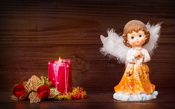 Christmas greeting card with candle and angels on wooden background.