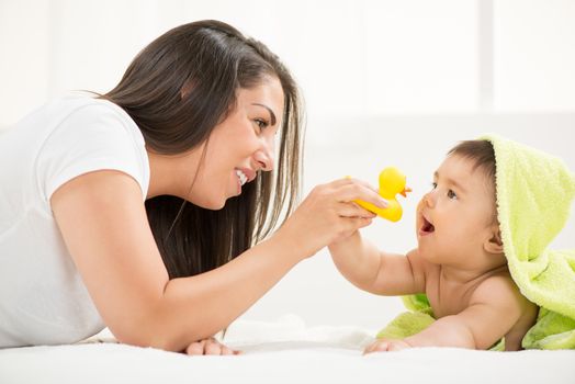 Mother and baby lying and playing after bathing