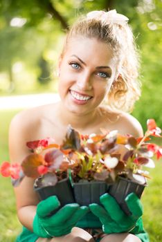 Smiling young woman planting flowers in the garden.