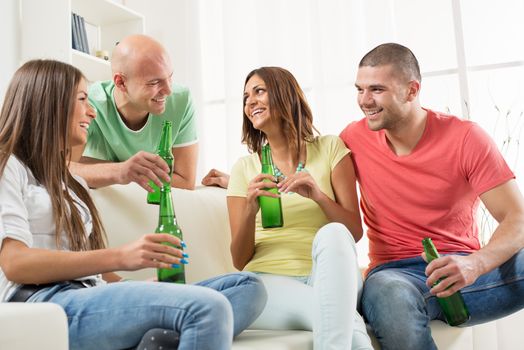 Four friends enjoying with beer together at the home party.