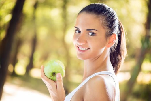 Young beautiful woman with apple in the nature
