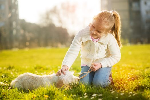 Little girl playing with her puppy dog in the park