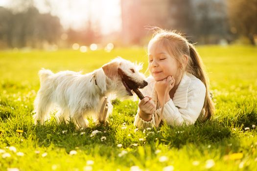 Little girl playing with her puppy dog in the park