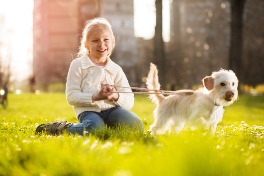 Little girl relaxing with her puppy dog in the park