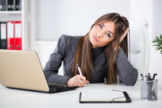 Worried Businesswoman in the office, sitting and thinking about problems. Looking at camera.