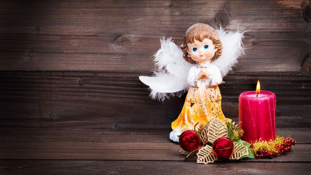 Christmas greeting card with candle and angels on wooden background.