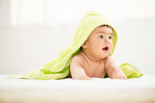 Cute baby boy lying under a towel