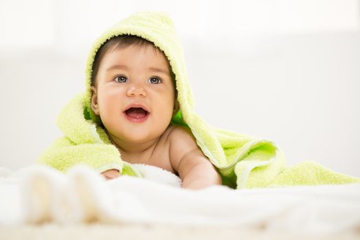 Cute baby boy lying under a towel