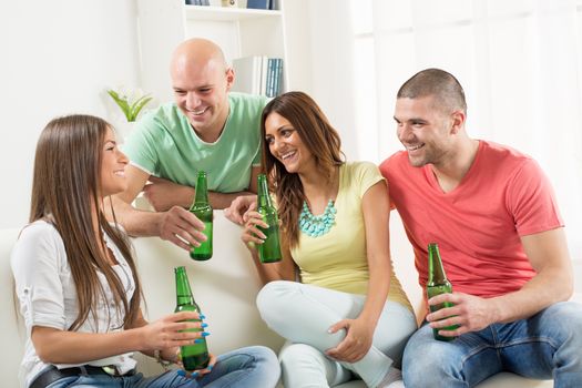 Four friends enjoying with beer together at the home party.